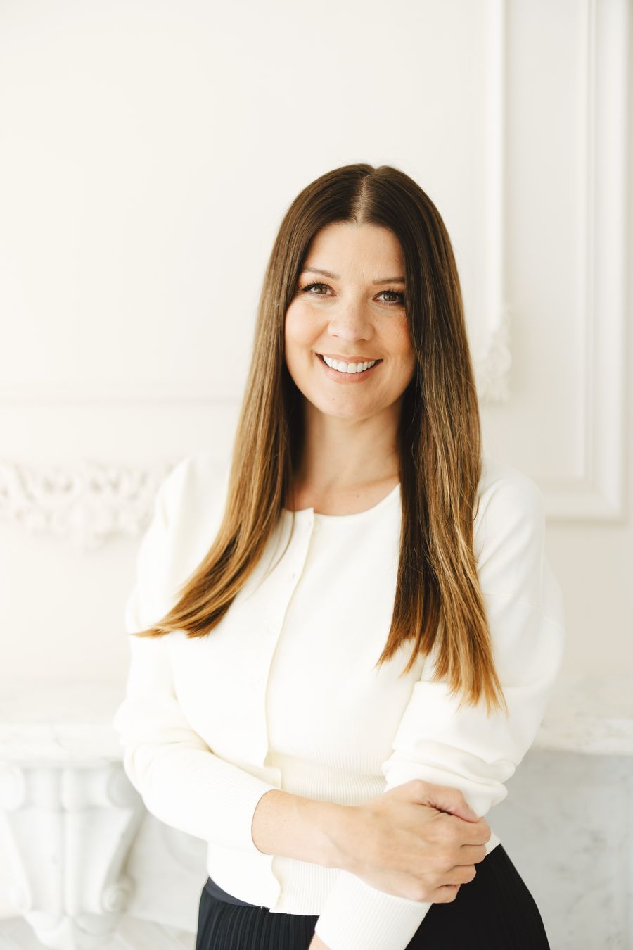 Dr. Stephanie Helfand in a cream cardigan, smiling, arms folded.